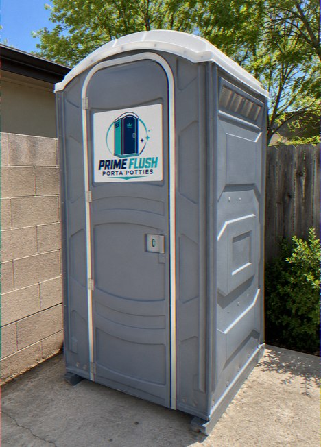 Portable toilet standing against a block wall in a residential yard